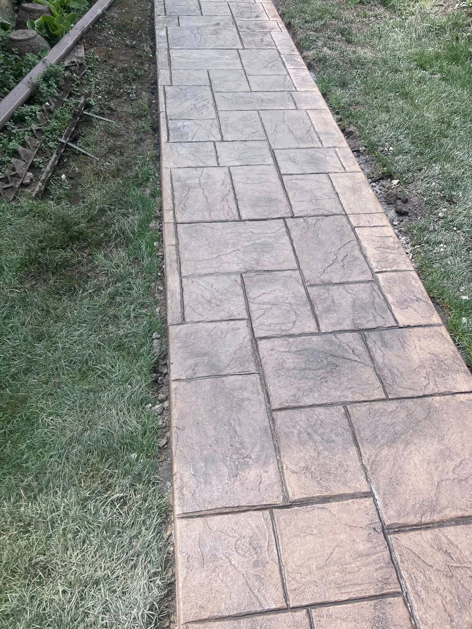 A brick walkway leading to a grassy area.