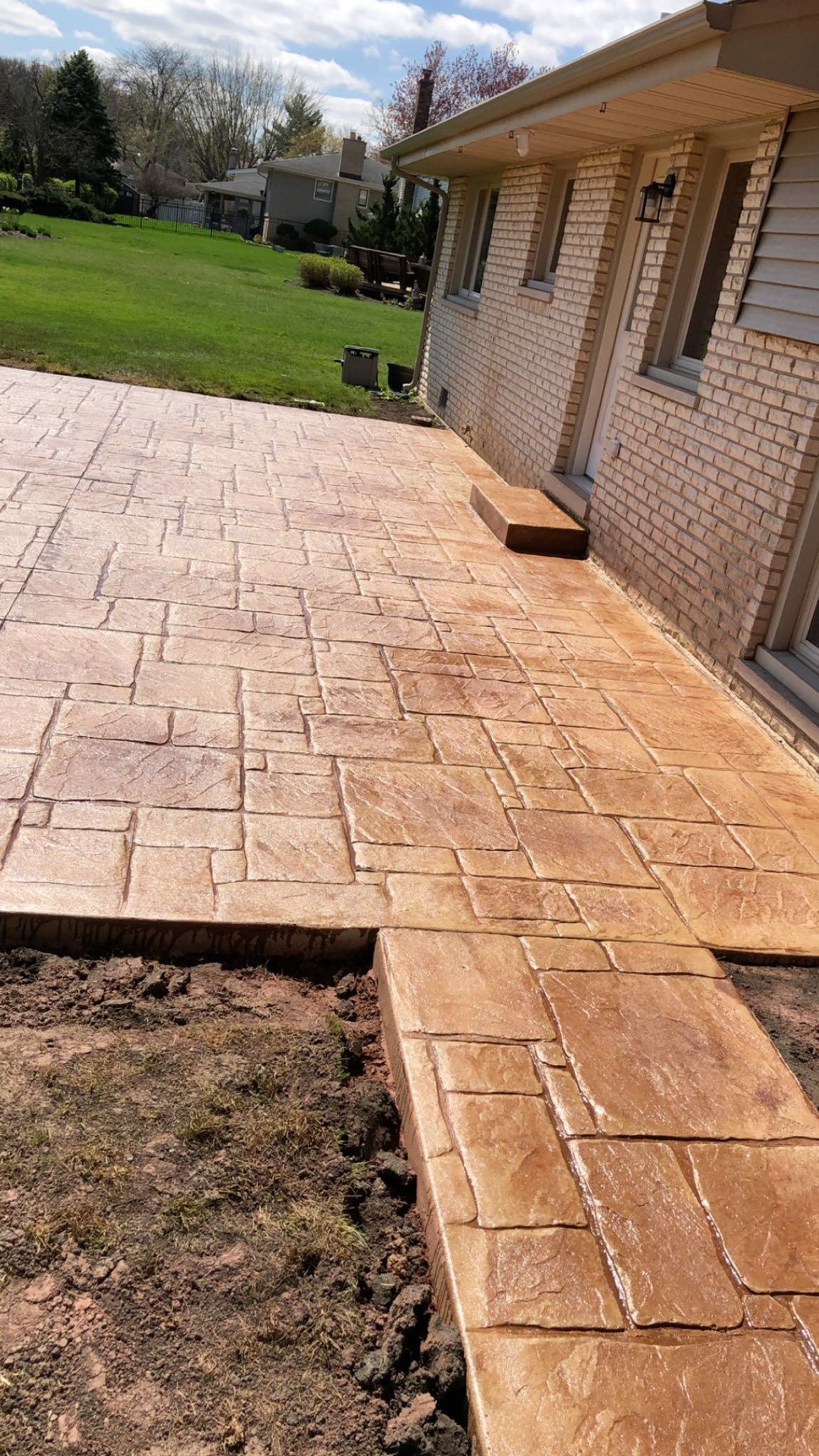 A concrete walkway is being built in front of a brick house.