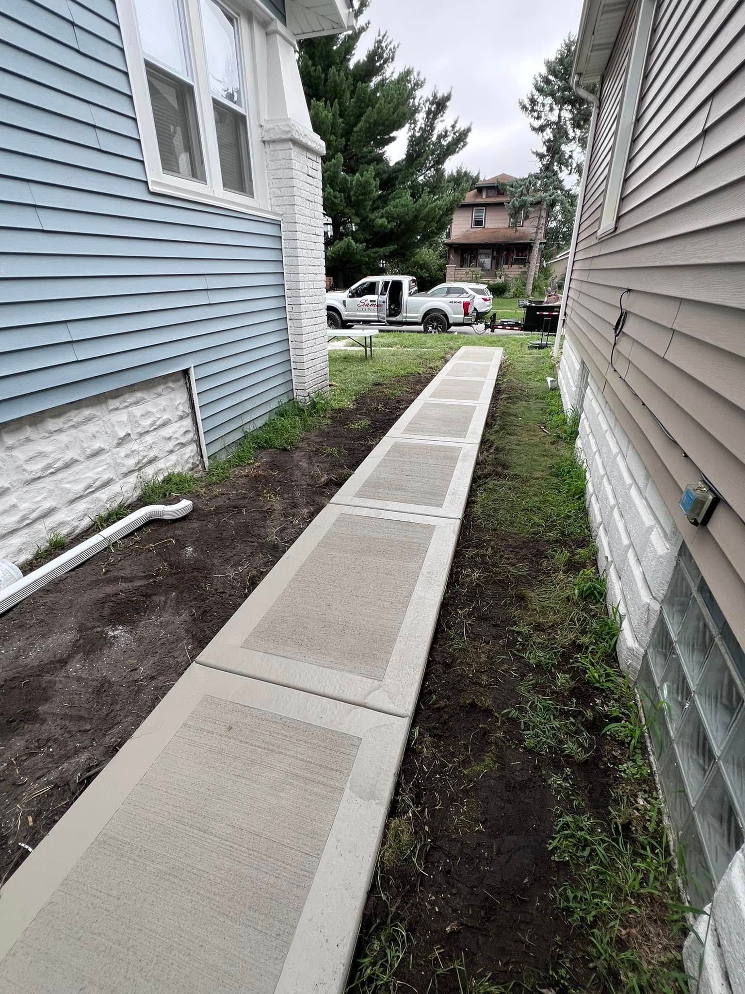 A sidewalk leading to a house with a truck parked on the side of it.