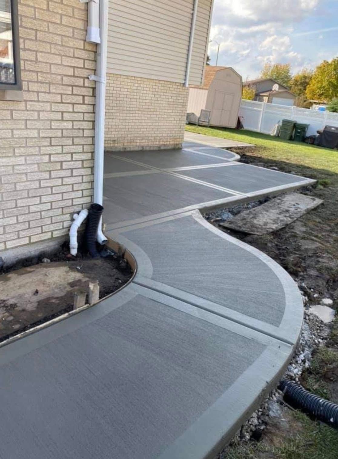 A concrete walkway is being built in front of a brick house.