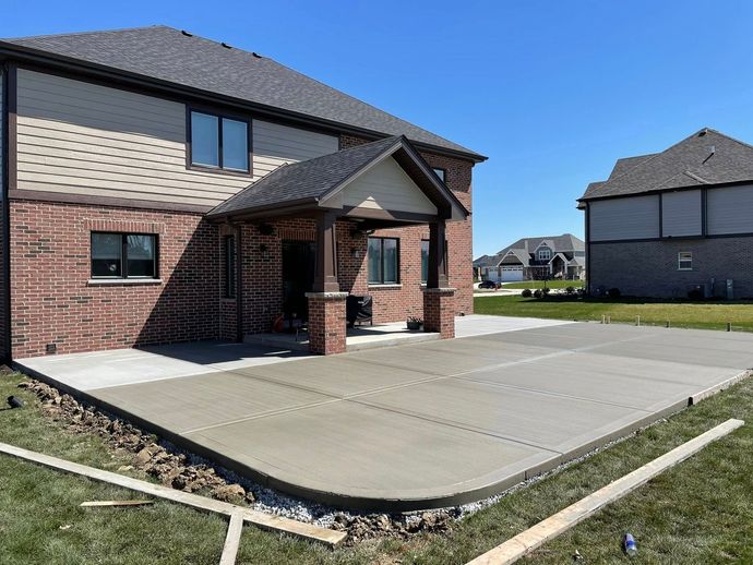 A brick house with a concrete driveway in front of it.