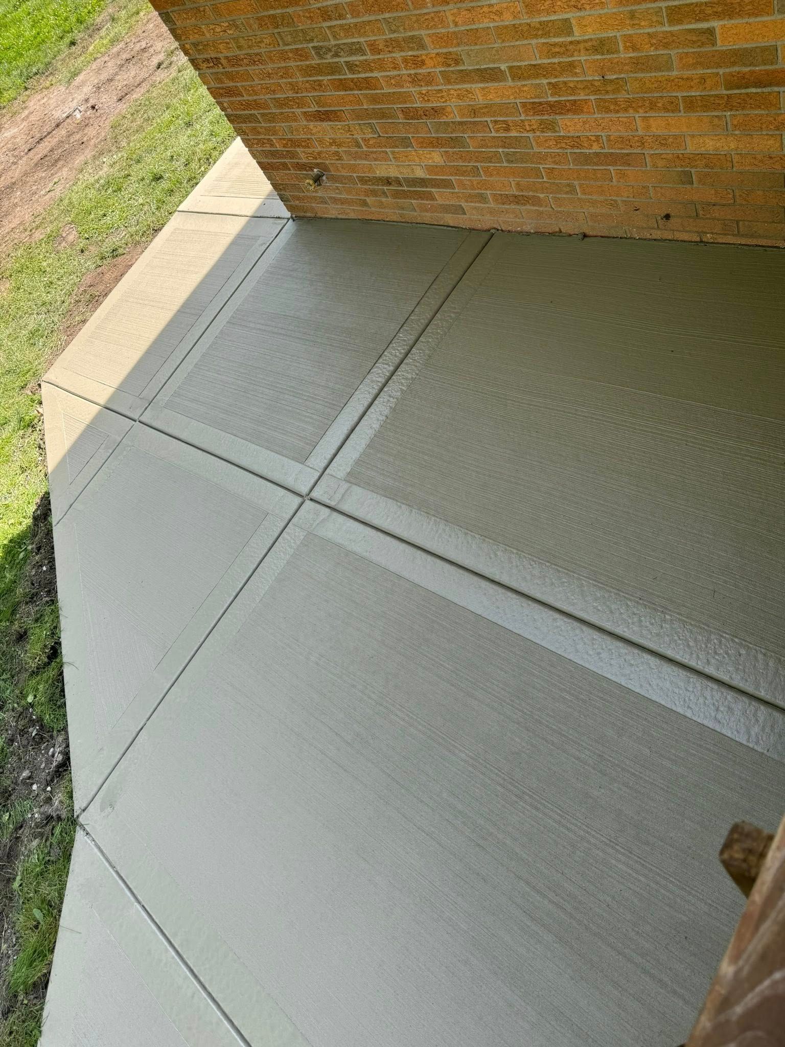 A concrete porch with a brick wall in the background.