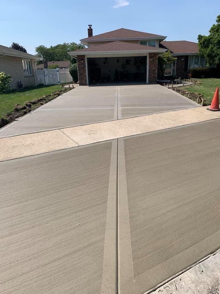 A concrete driveway leading to a house with a garage.