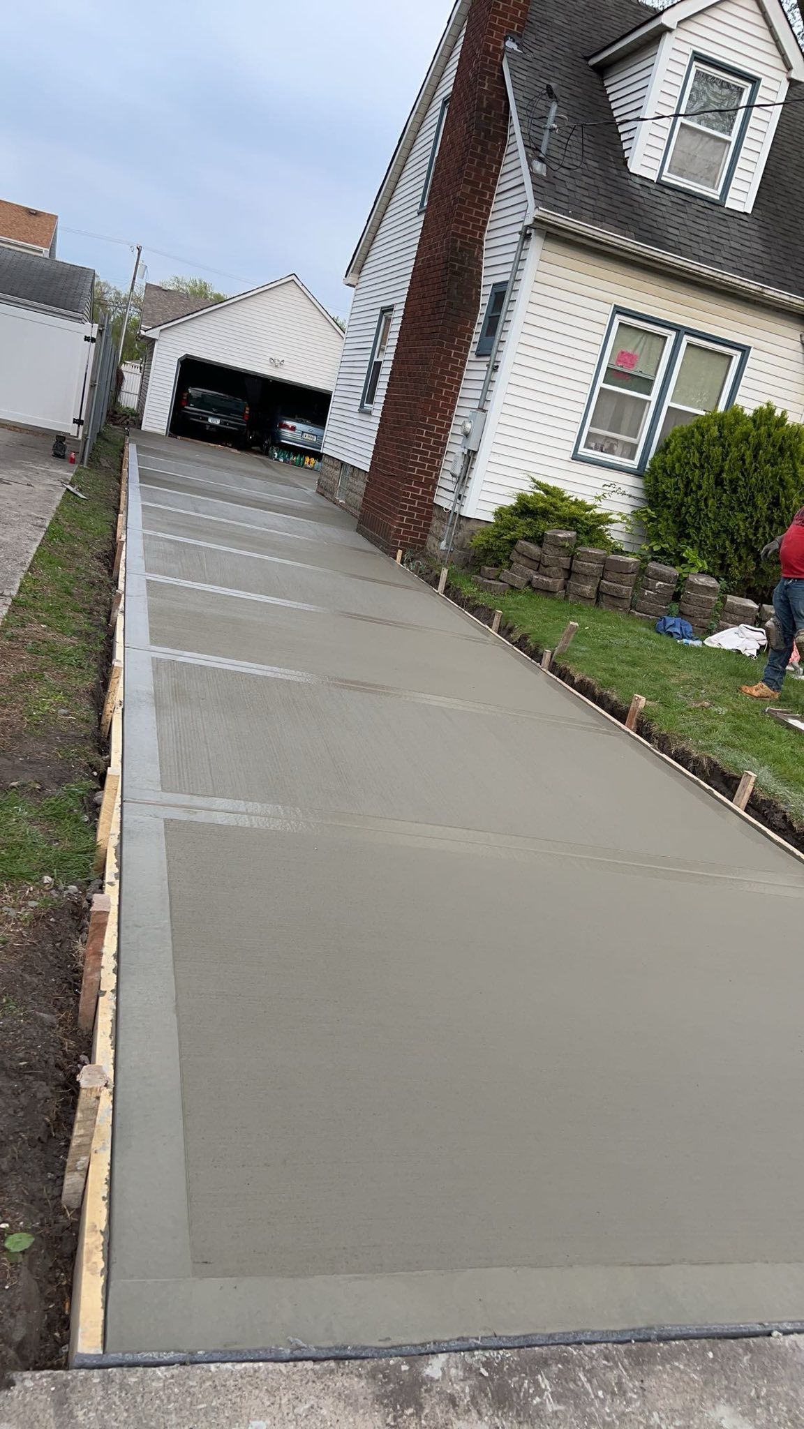 A concrete driveway is being built in front of a house.