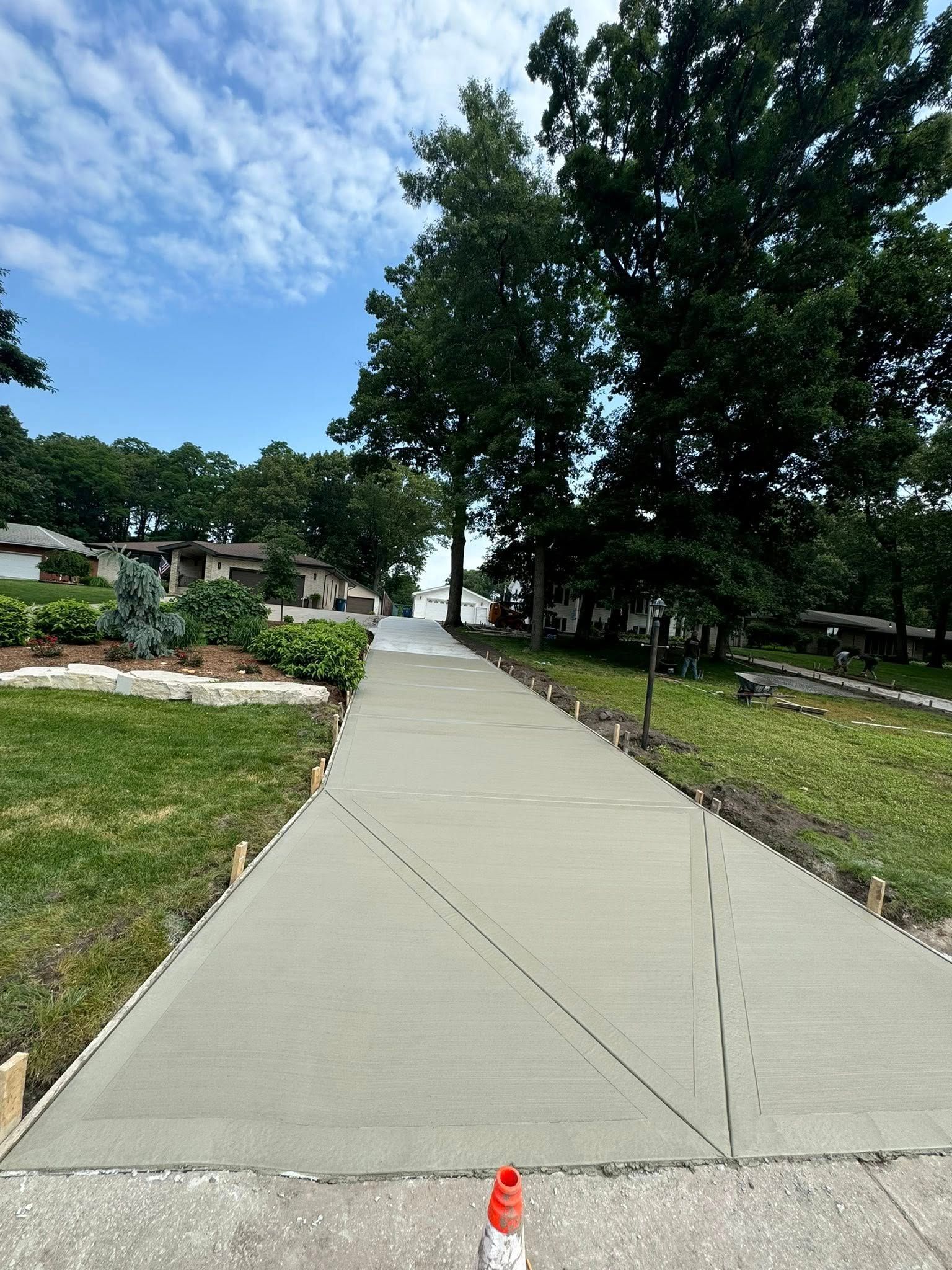 A concrete driveway leading up to a house with trees on both sides.
