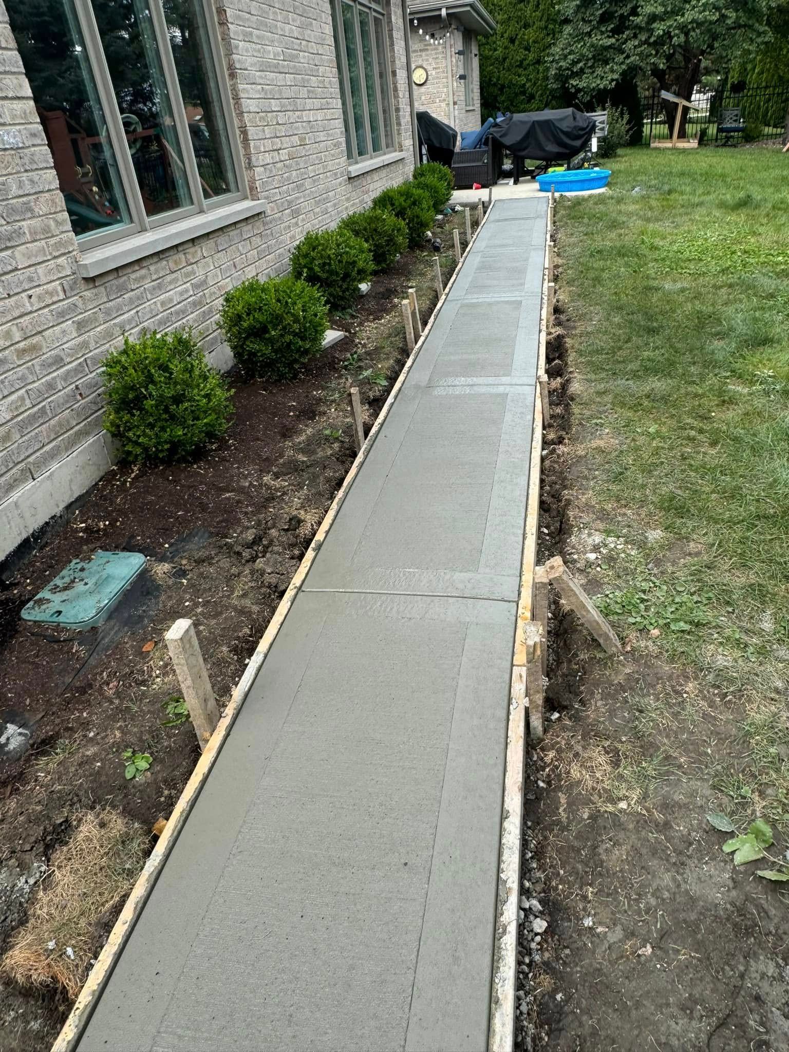 A concrete walkway is being built in front of a house.