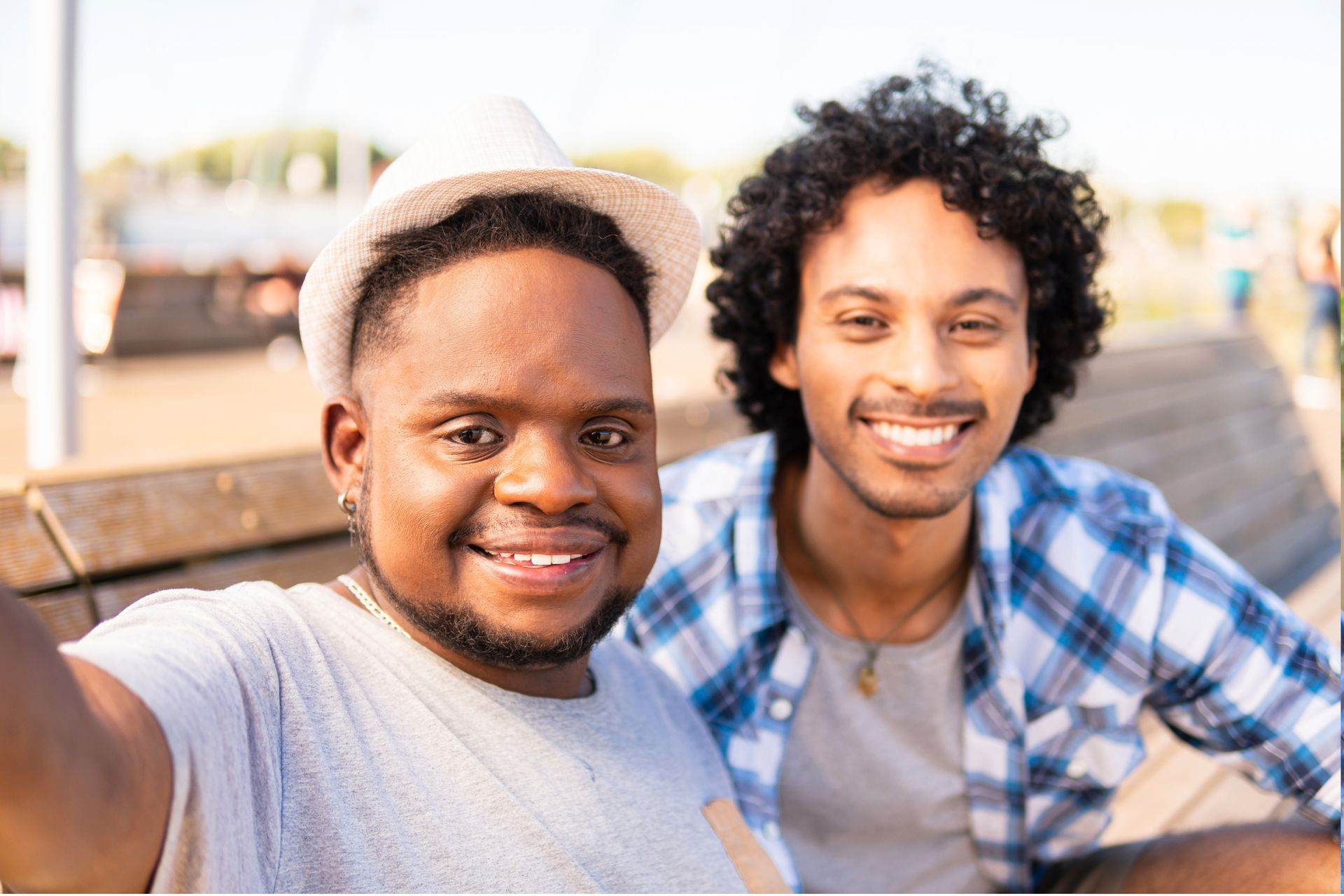 Two men are taking a selfie together on a bench.