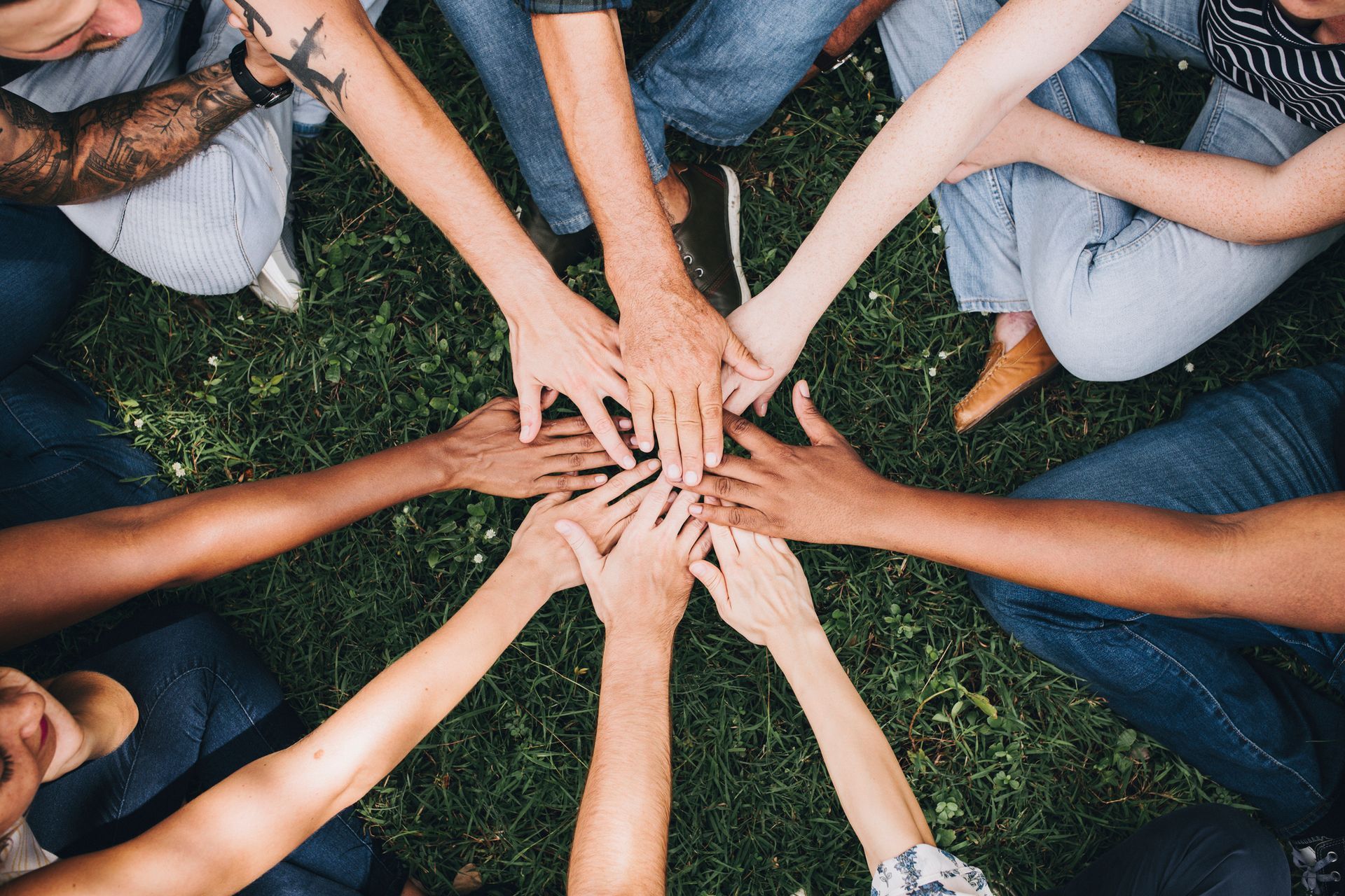 A group of people are putting their hands together in a circle.