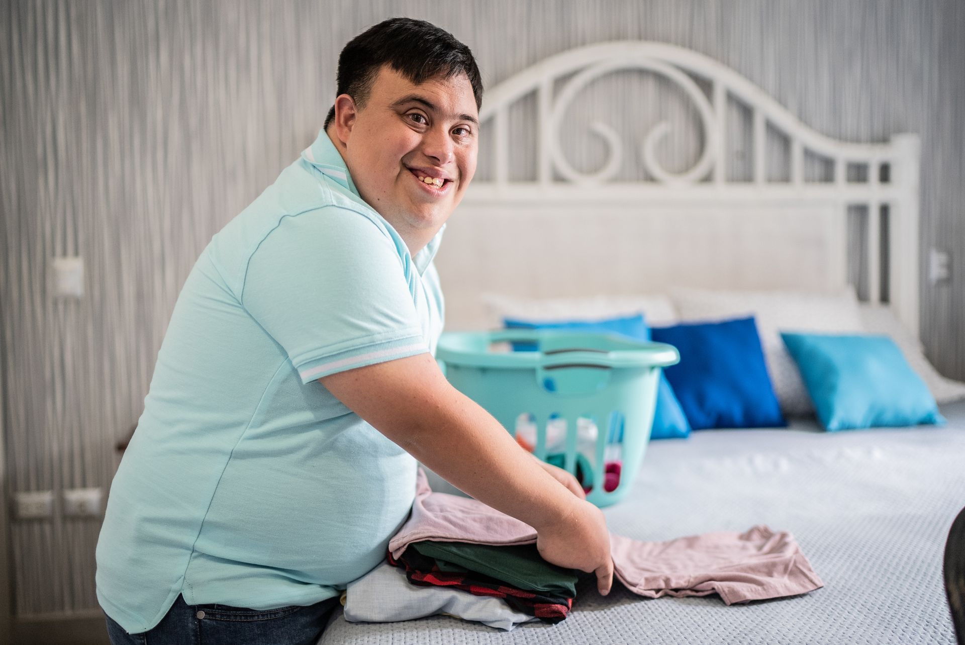 A man folding his laundry on a bed.