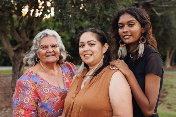 Three women are posing for a picture together in a park.