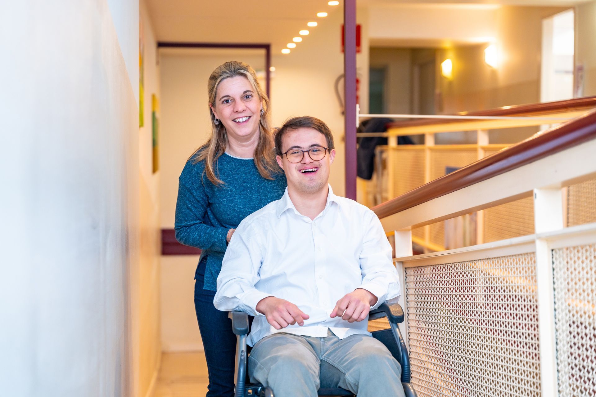 A woman standing behind a man in a wheelchair.