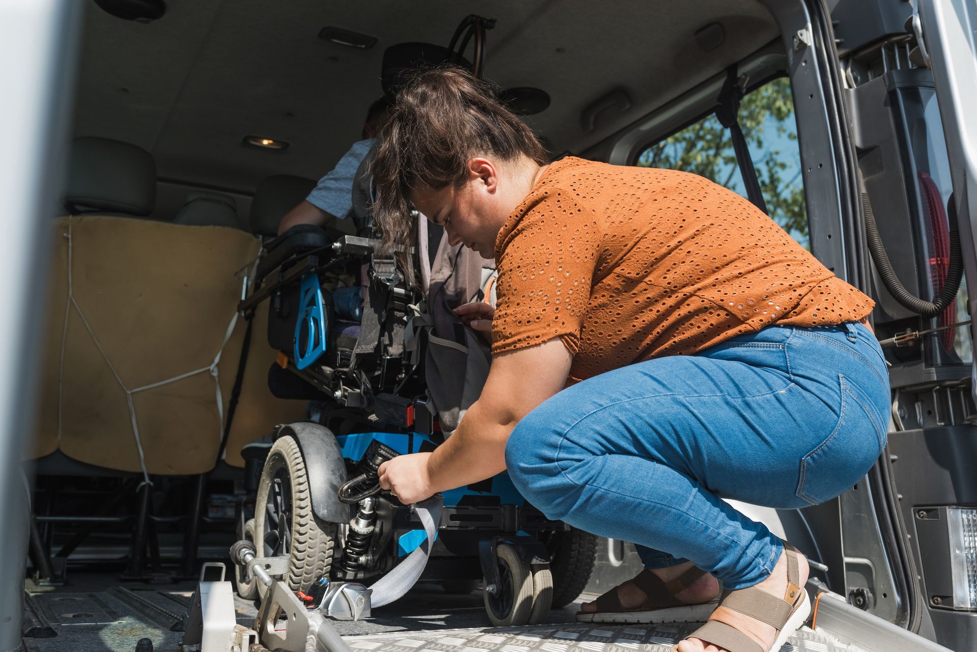 A woman is securing a wheelchair in the back of a van.