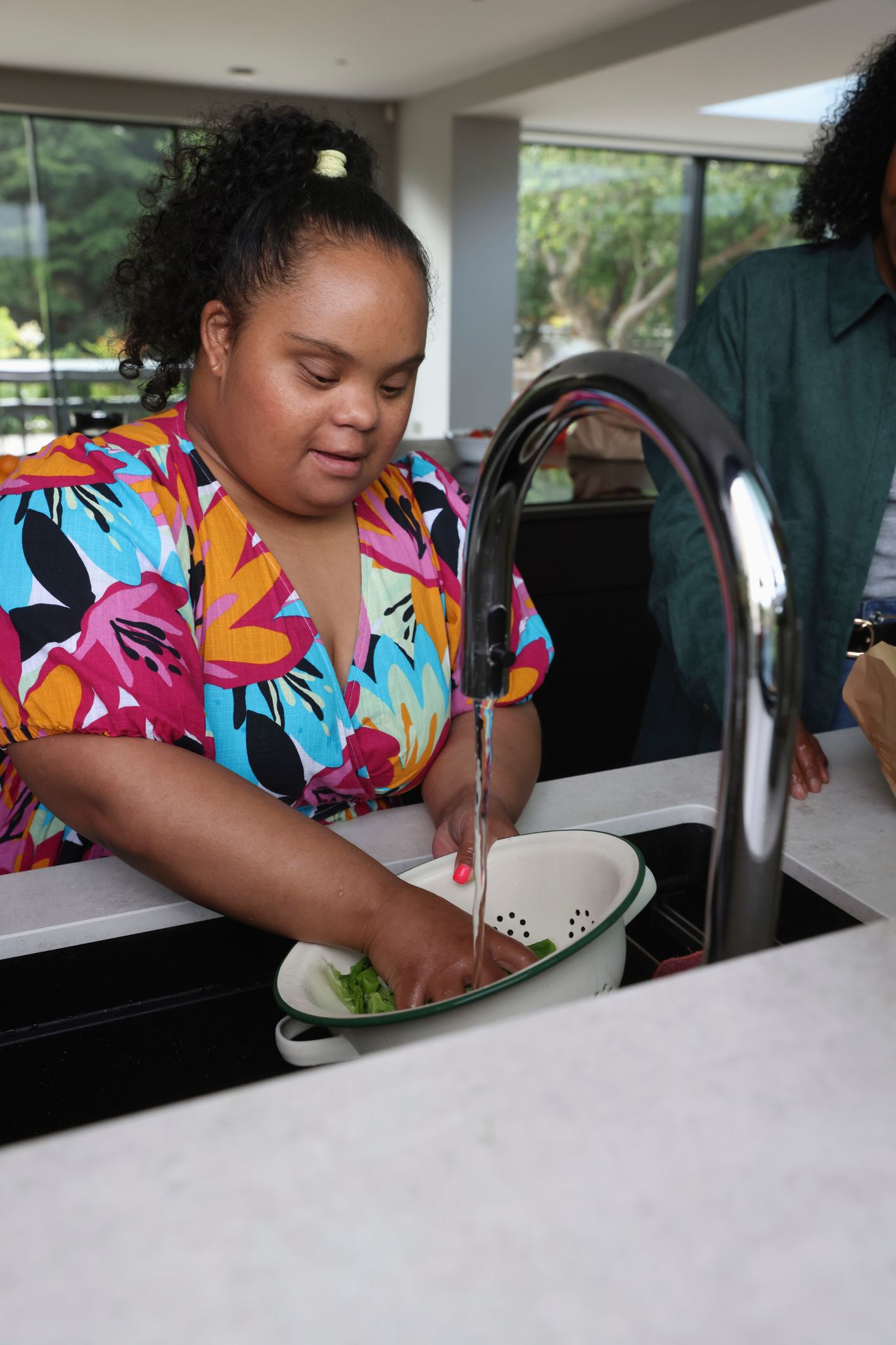 A woman is washing dishes in a kitchen sink.