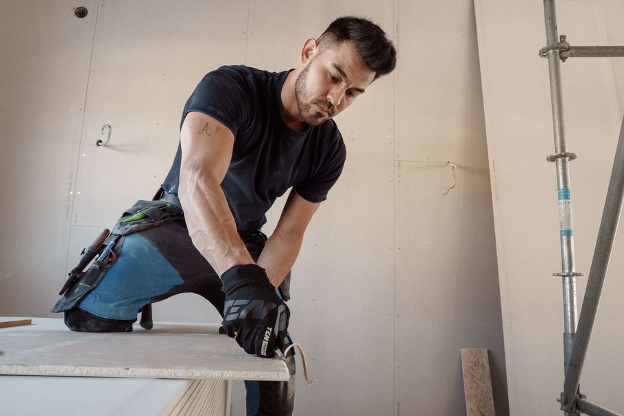Worker kneeling on a countertop, using a hand tool during interior construction work