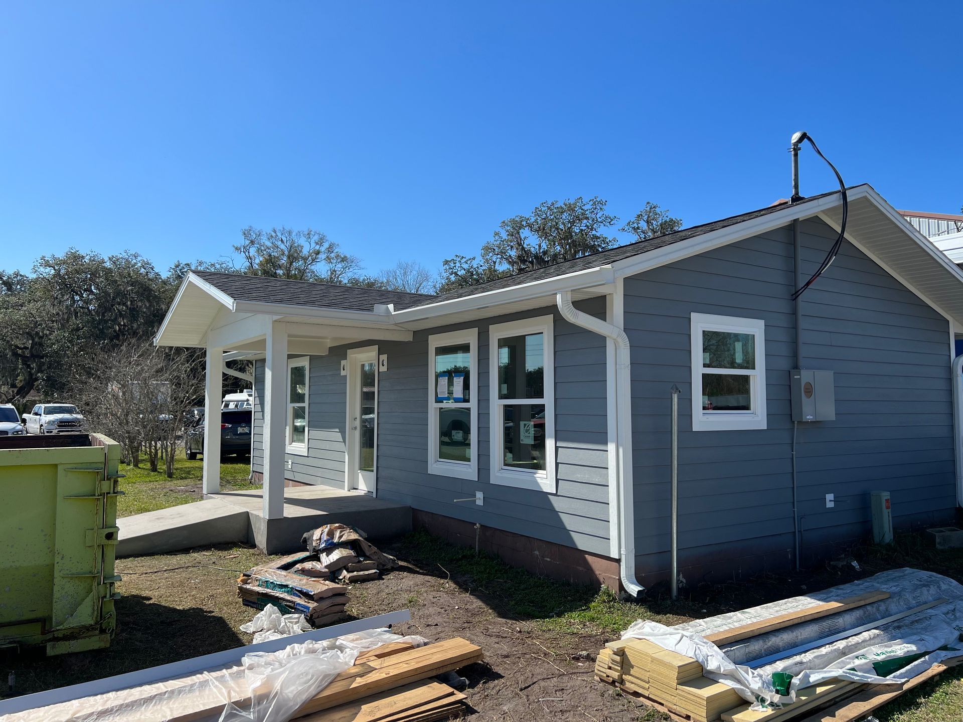 New construction home with gray siding, white trim, and construction materials.