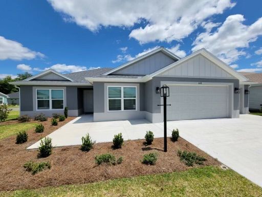Blue and white suburban house with a garage, landscaped yard, and a blue sky.