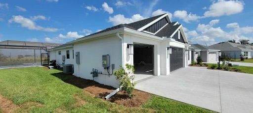 A white house with a black garage door and a driveway on a sunny day.