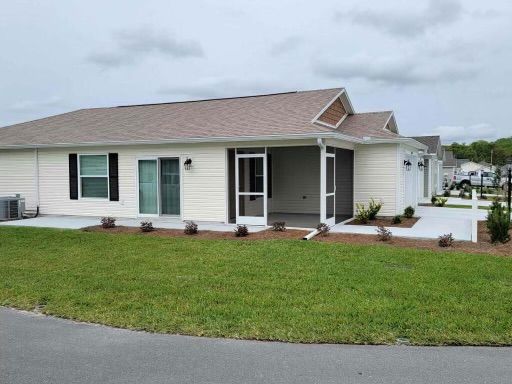 White house with a screened-in porch and tan roof, set on a green lawn under a cloudy sky.