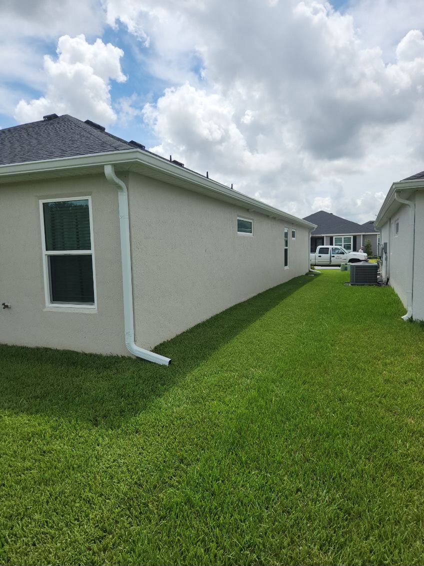 Side view of two houses with green grass and blue sky.