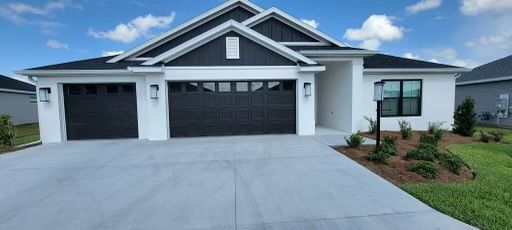 Modern white house with a black roof and garage doors on a sunny day.