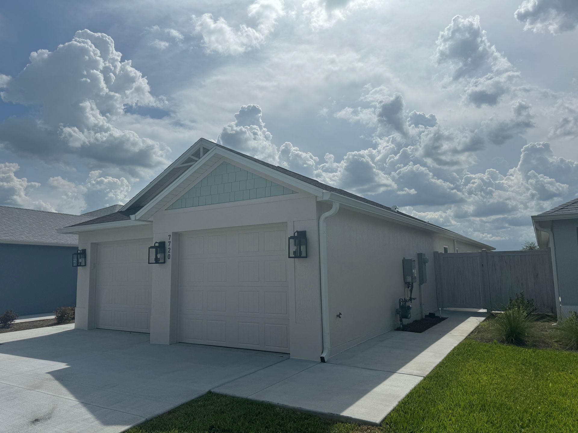 White garage with two doors, light blue trim, under a cloudy sky.