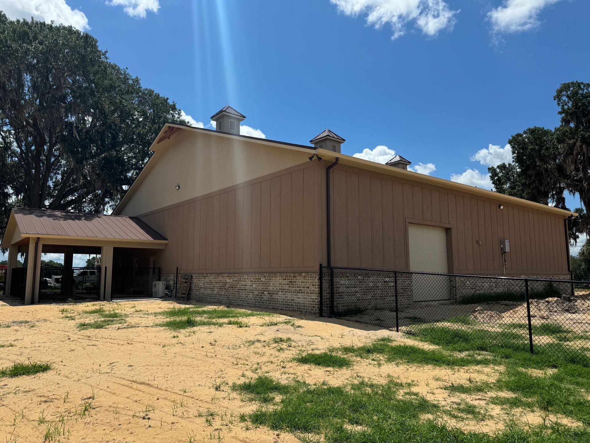 Tan-colored building with a portico on a sandy lot under a blue sky.
