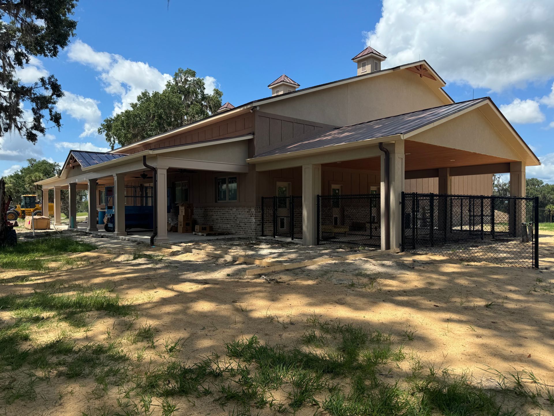 A beige, single-story building under construction with a covered porch on a sunny day.