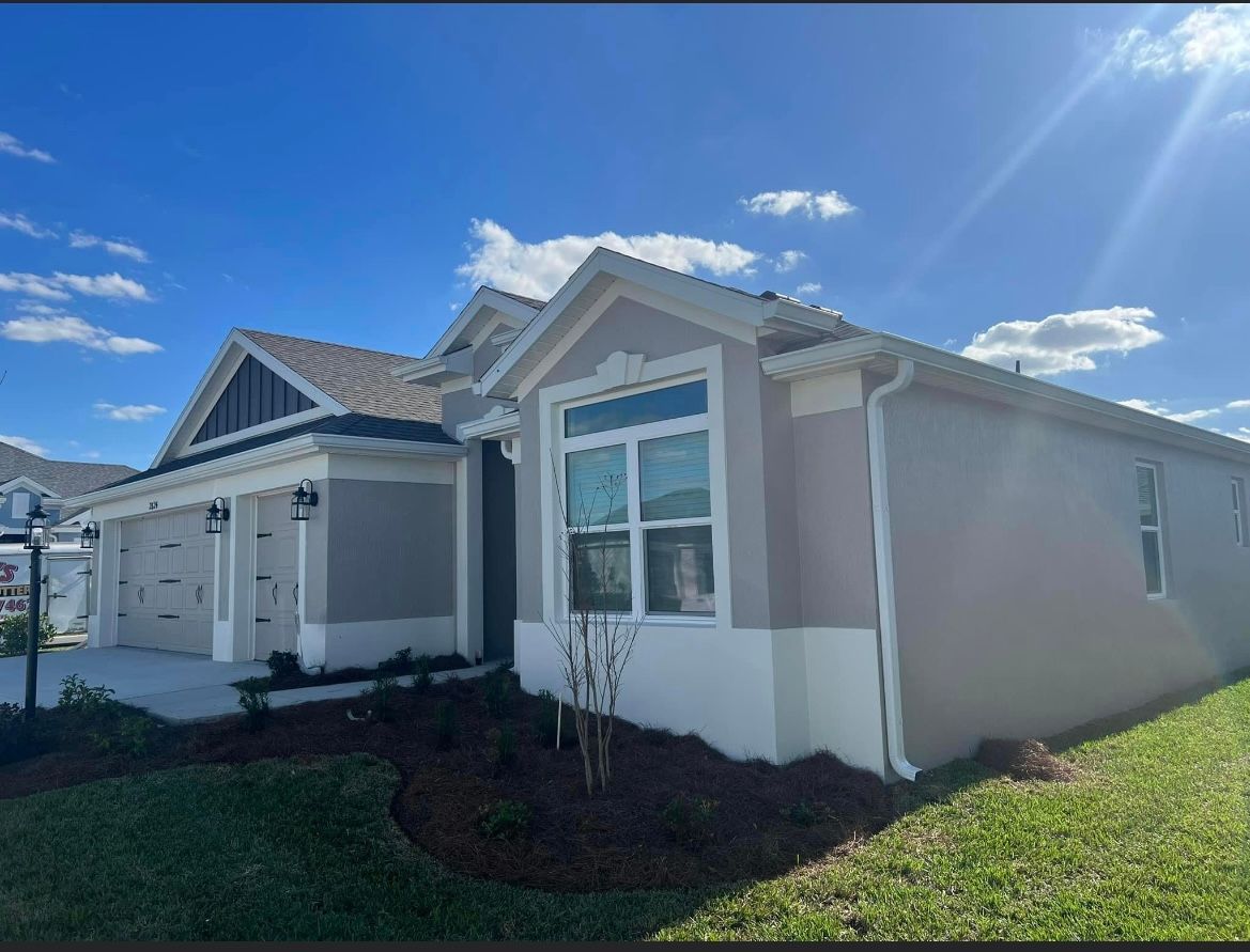 A light gray house with white trim against a blue sky with clouds.