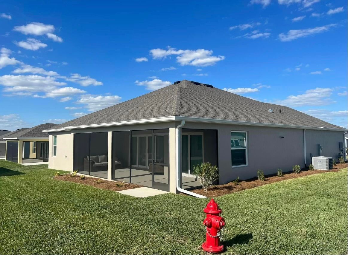 Tan, single-story house with screened patio, gray roof, and red fire hydrant in front.