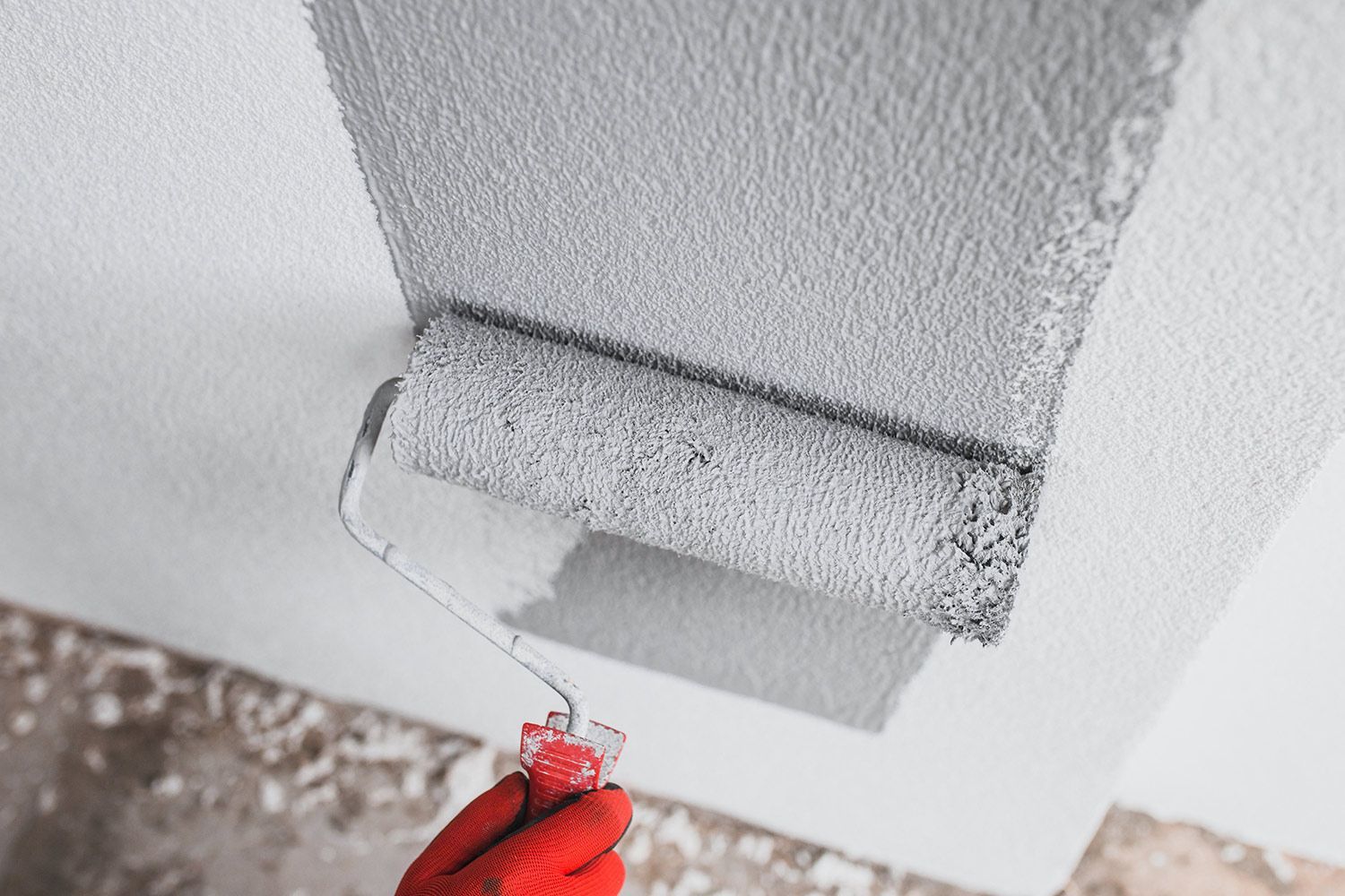 Worker with roller painting the wall