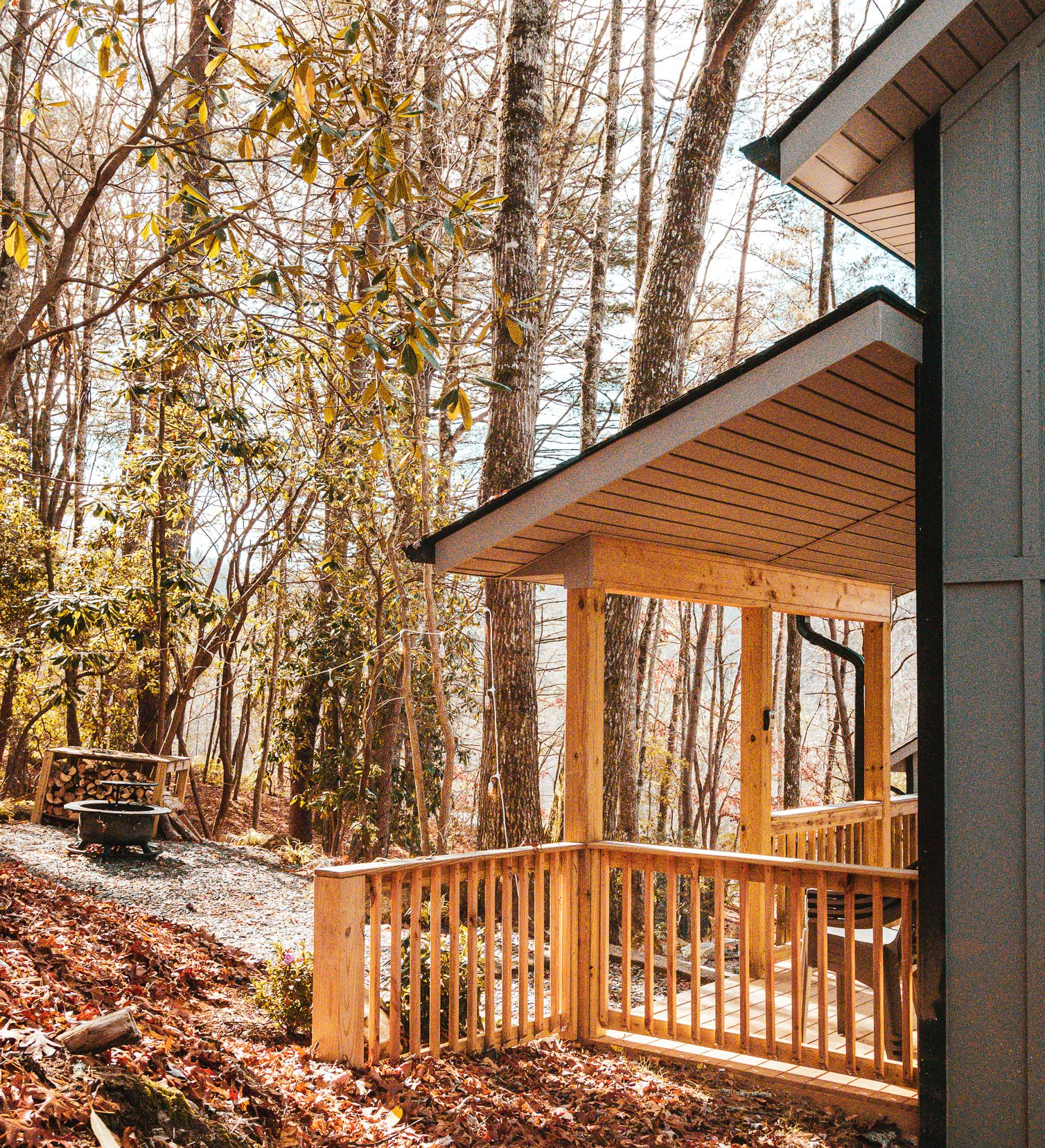 Cabin with wooden porch and railing in a wooded area.