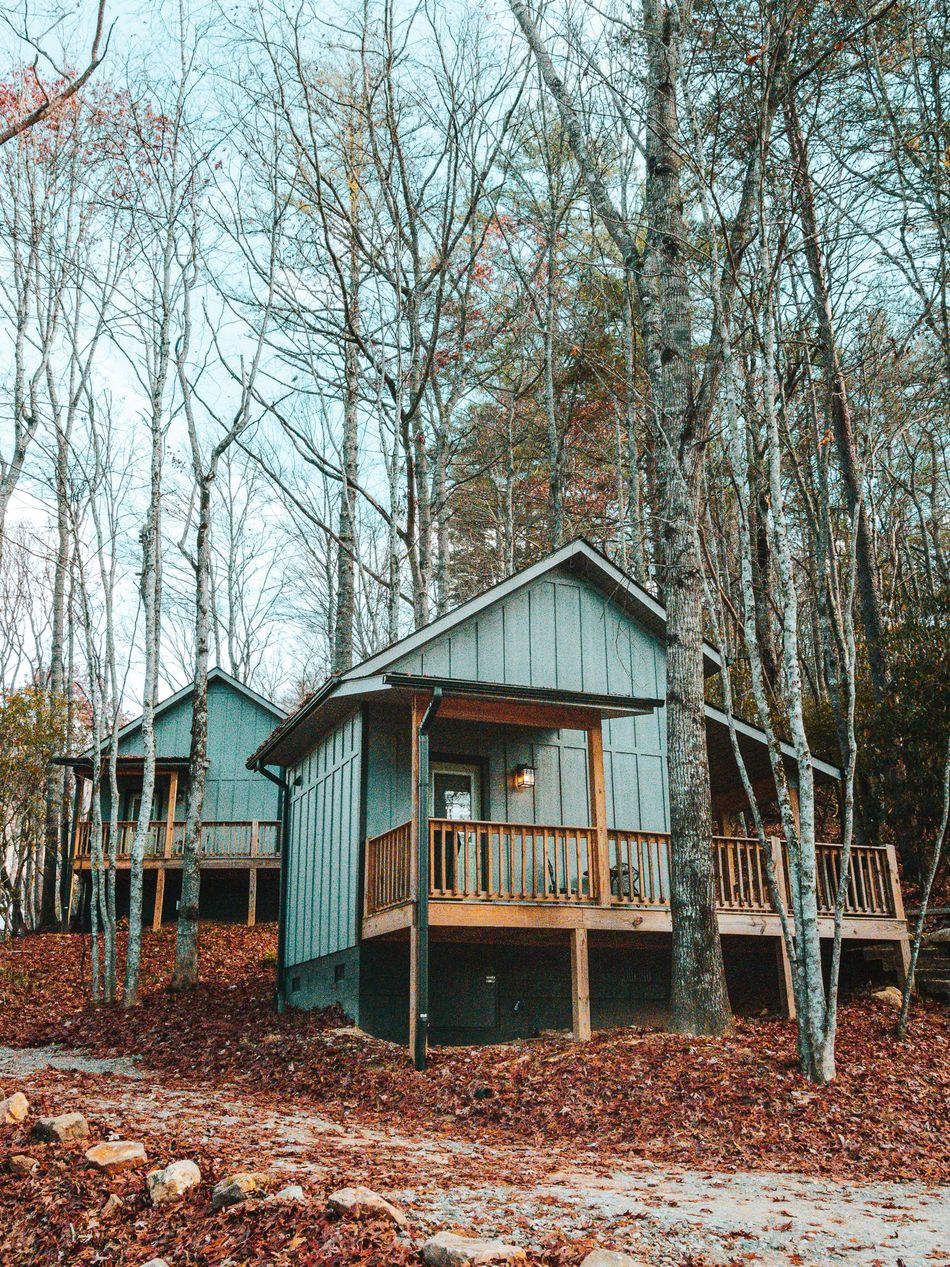 Secluded cabins Grey cabins nestled in a wooded area with bare trees and a gravel driveway.