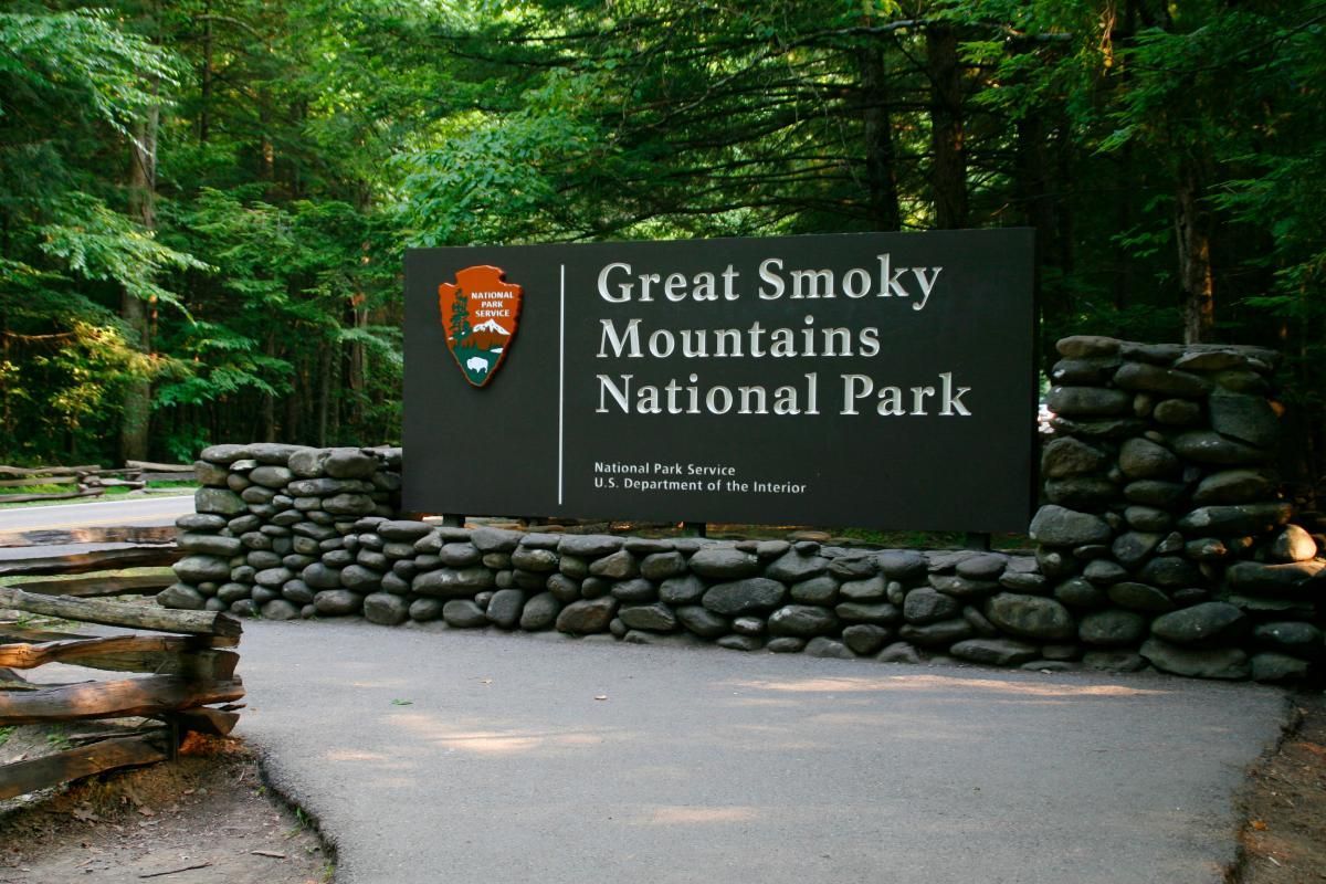 Great Smoky Mountains National Park entrance sign, featuring a rock border and lush green trees.