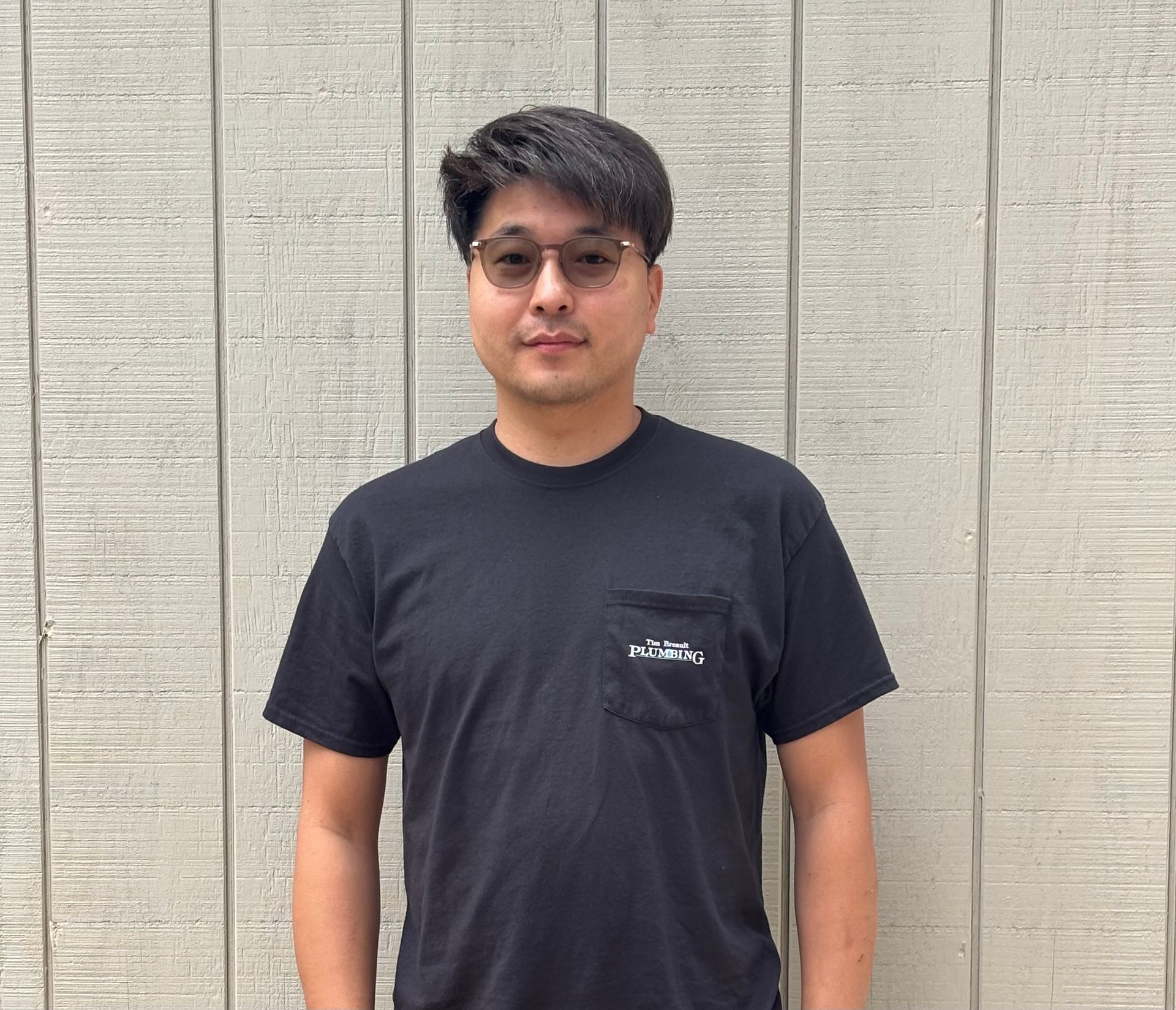 Man with beard and crossed arms smiling in front of a light gray wall.