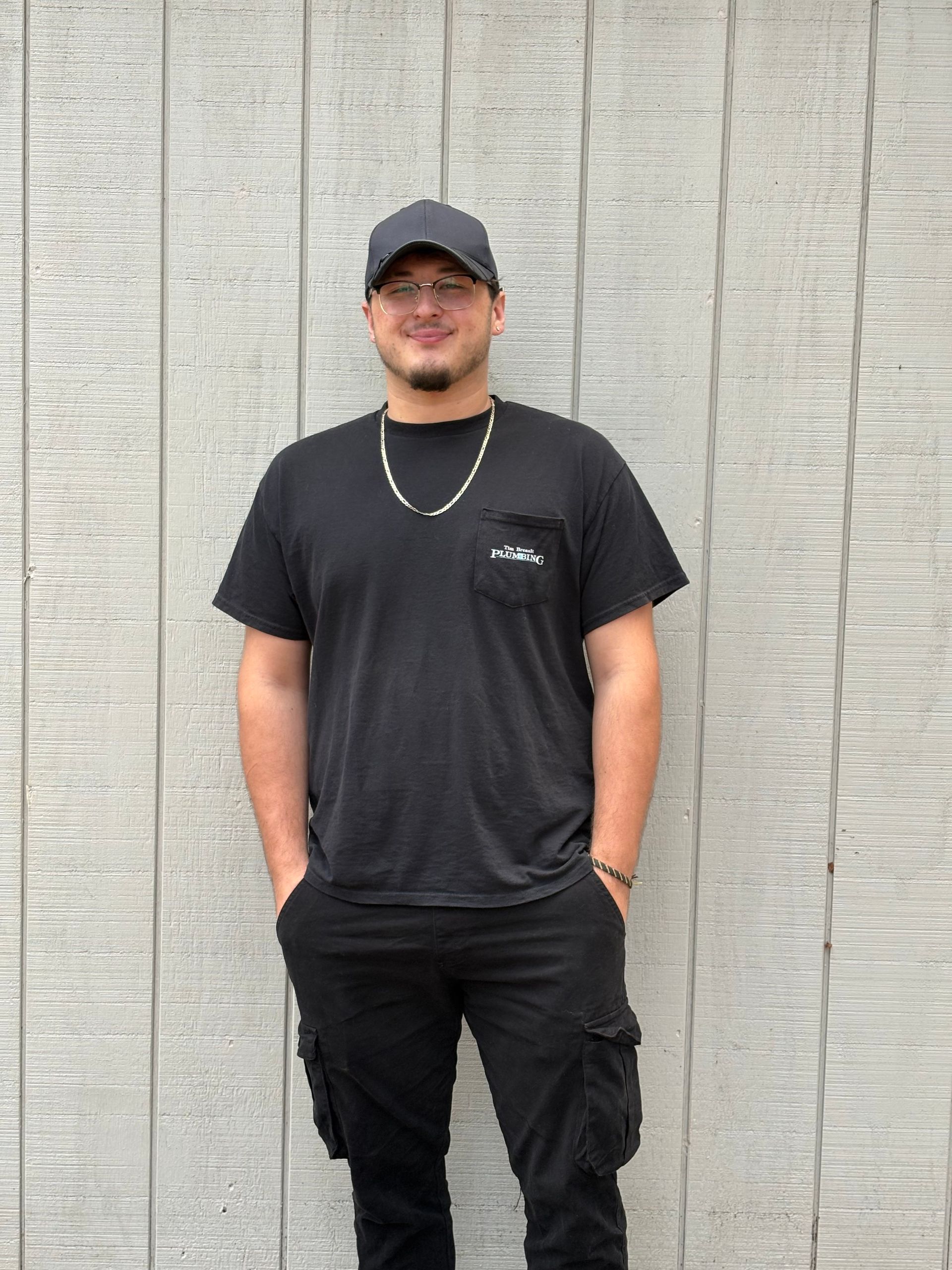 Man with beard and crossed arms smiling in front of a light gray wall.