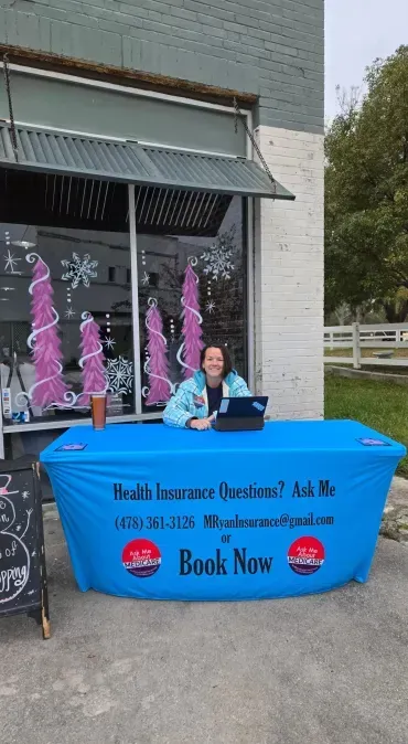 A woman sitting at a table with a blue table cloth that says book now