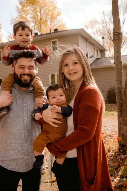 A family is posing for a picture in front of a house.