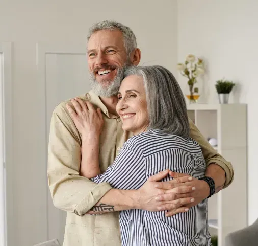 A man and a woman are hugging each other in a living room.