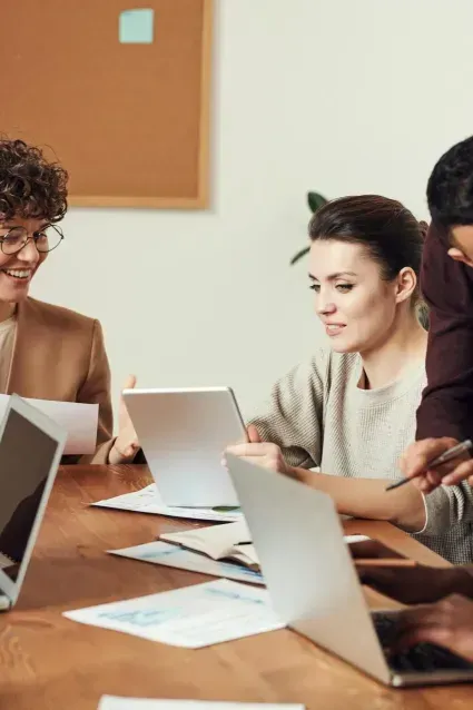 A group of people are sitting at a table with laptops.