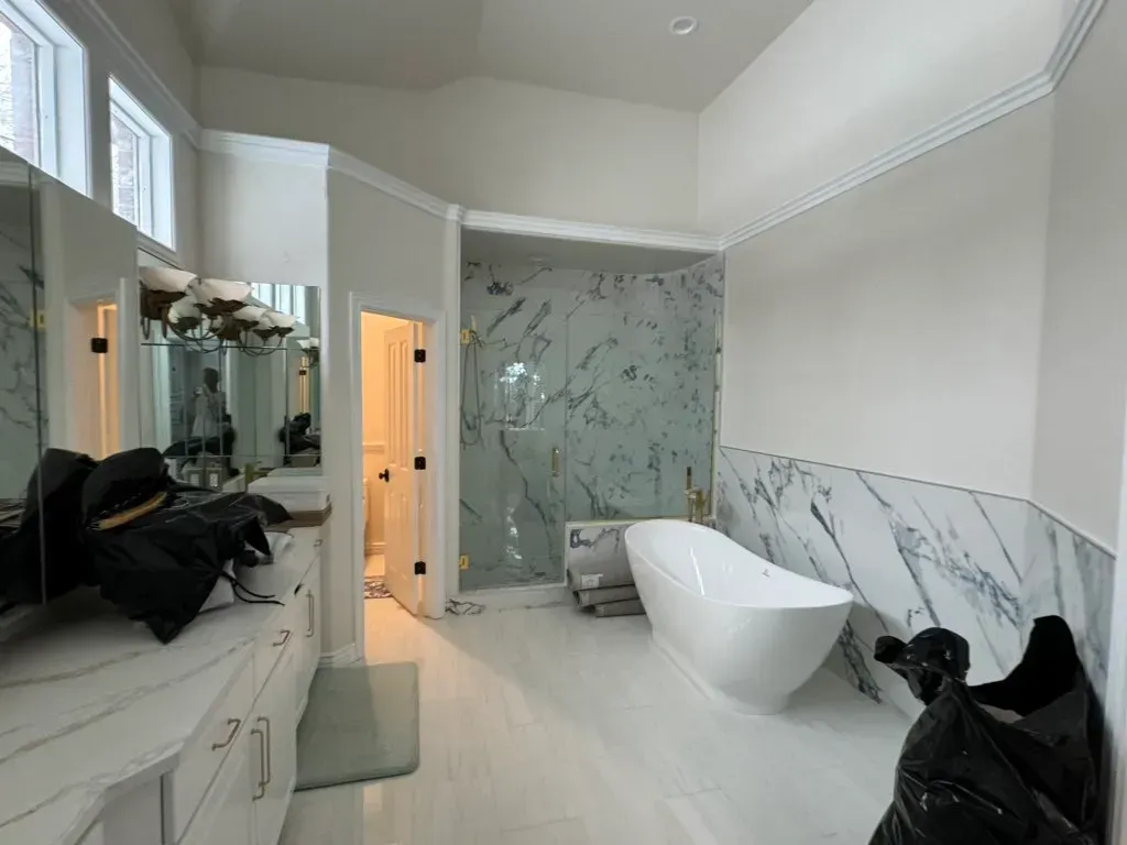 A bathroom with a bathtub , sinks , mirrors and marble walls.