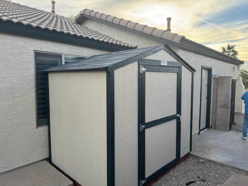A small shed is sitting in front of a house.