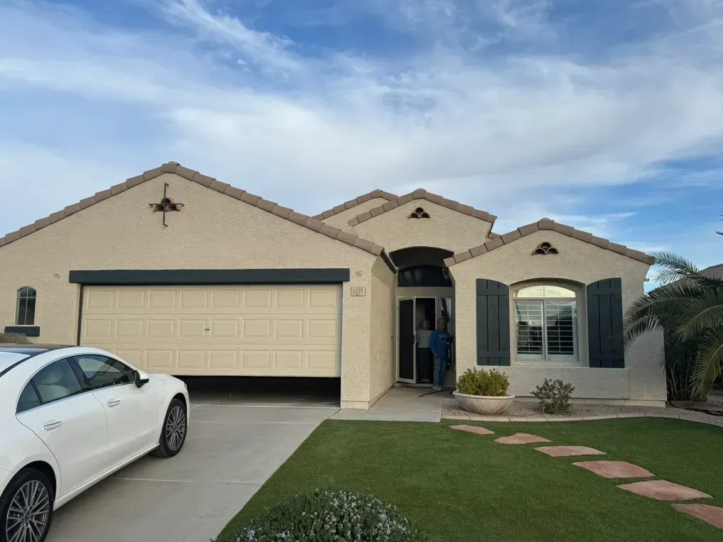 A white car is parked in front of a house.