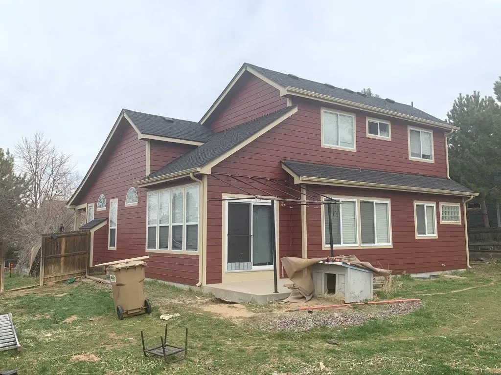 A large red house with a black roof is sitting on top of a lush green field.