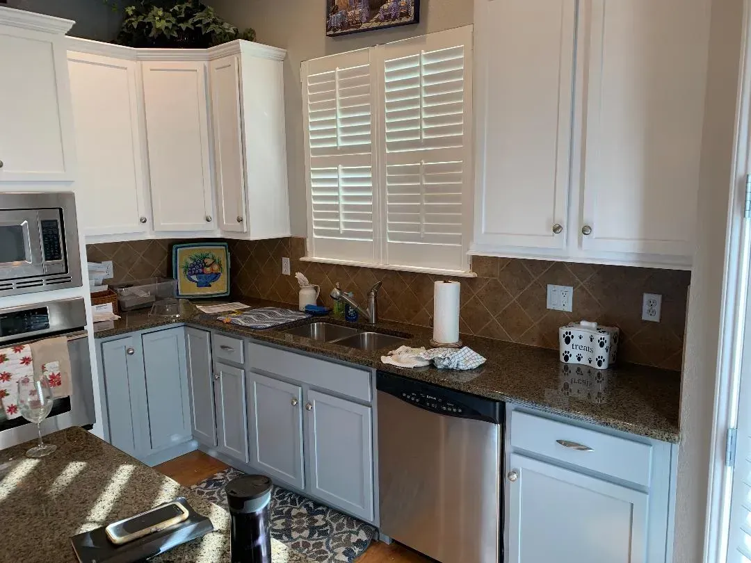 A kitchen with white cabinets , granite counter tops , and stainless steel appliances.