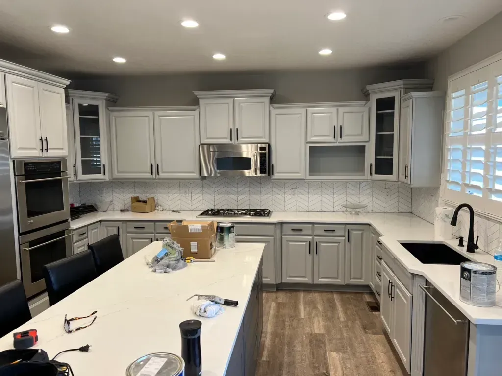 A kitchen with white cabinets , stainless steel appliances , and a large island.