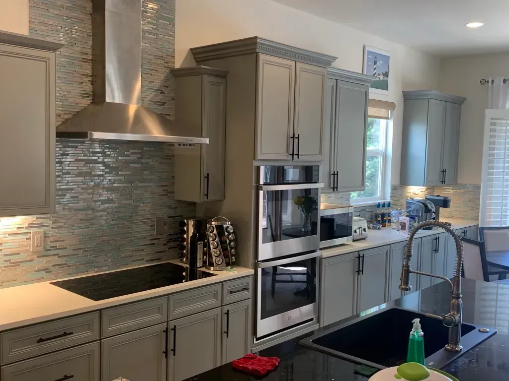 A kitchen with gray cabinets , stainless steel appliances , a sink , and a stove.