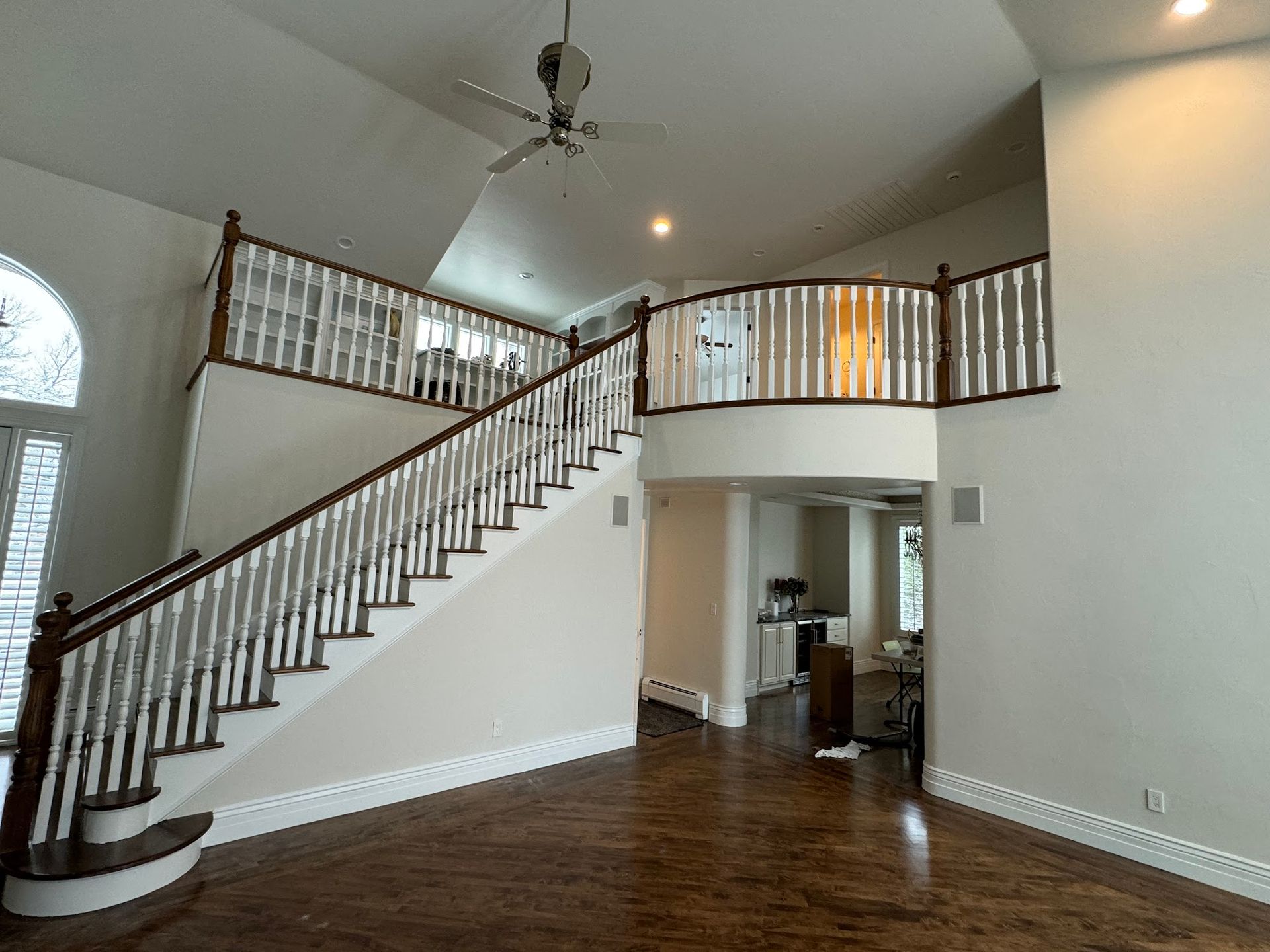 A living room with a staircase and a ceiling fan.