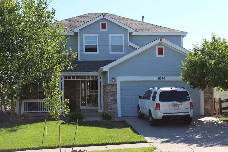 A white suv is parked in front of a blue house