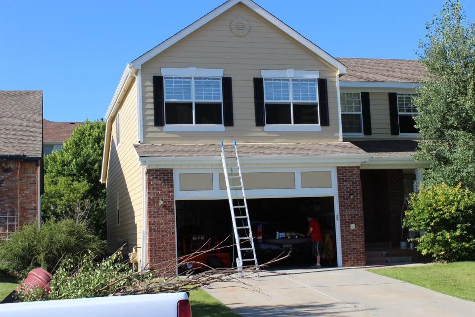 A house with a ladder in front of it and a truck parked in front of it.