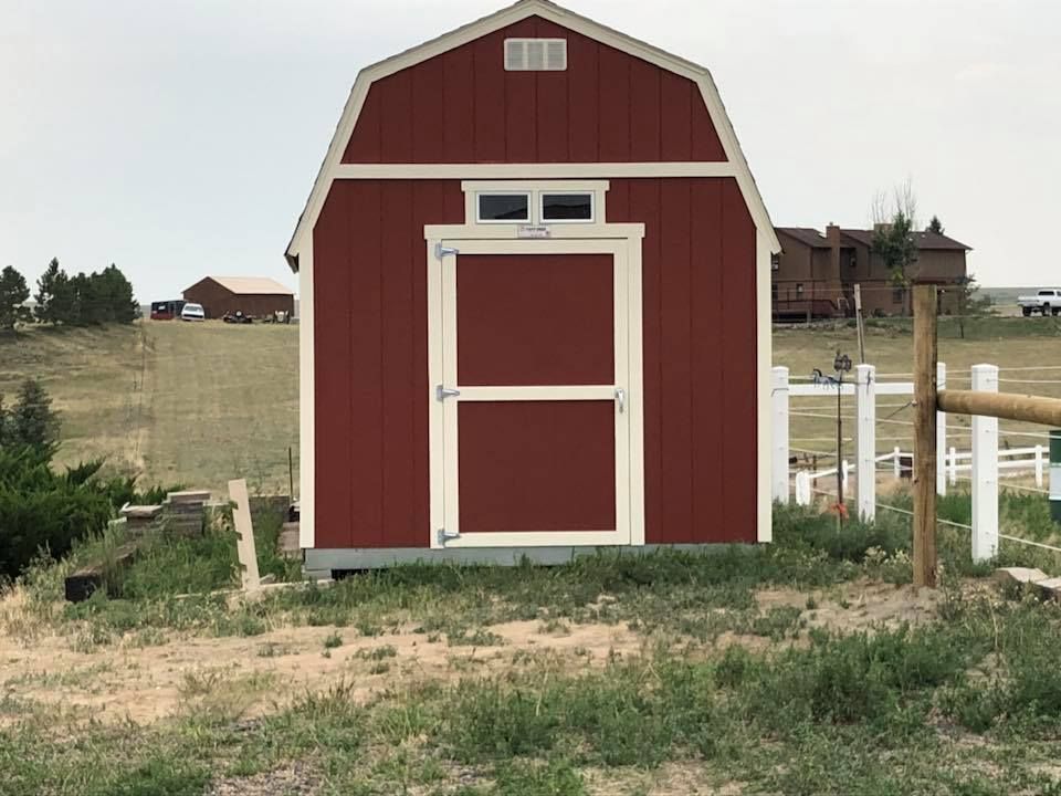 A red barn with a white trim sits in the middle of a grassy field